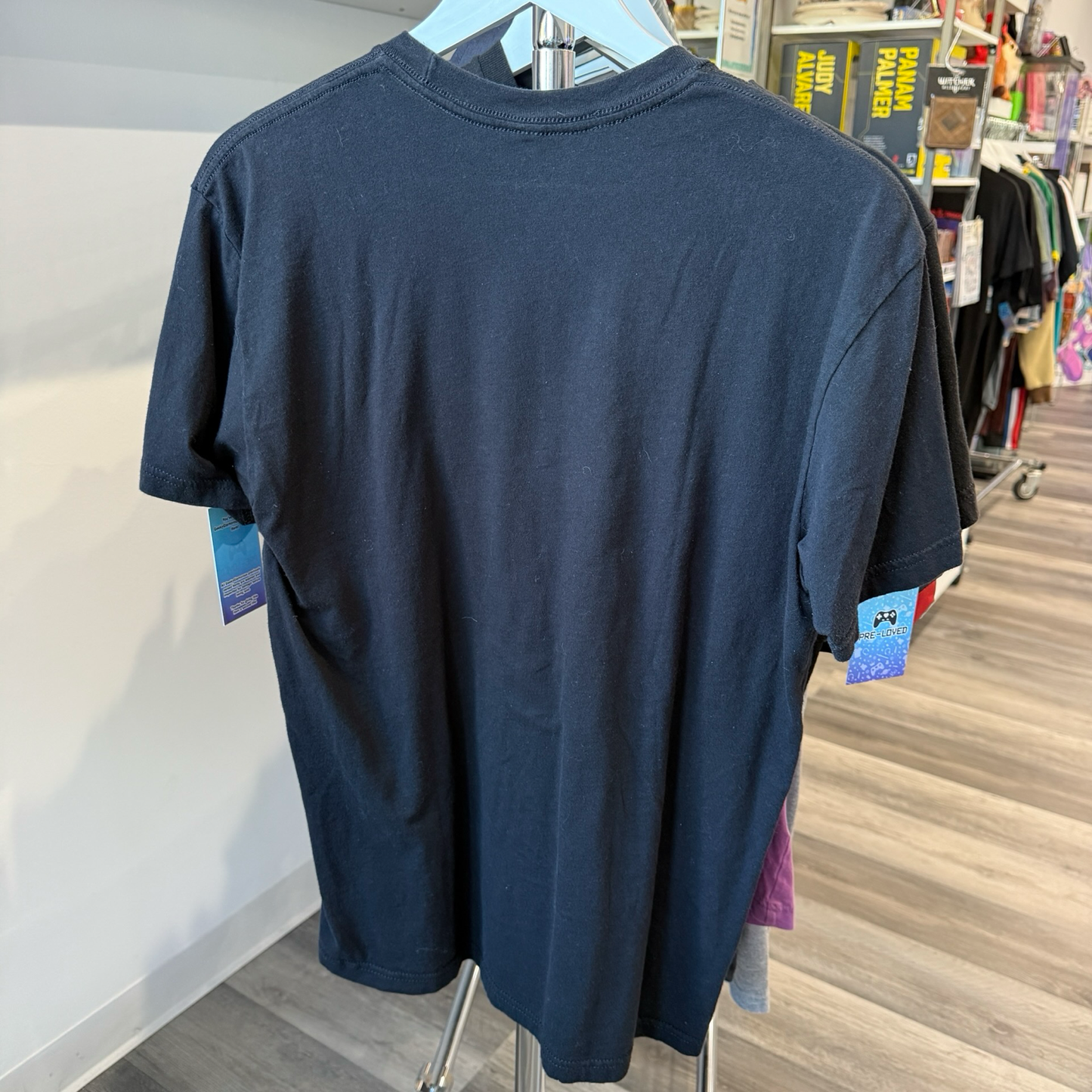 Back view of a black tshirt hanging on a rack