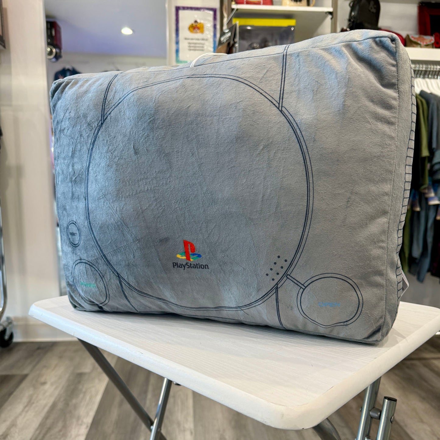 PlayStation controller-shaped pillow with logo in a store setting