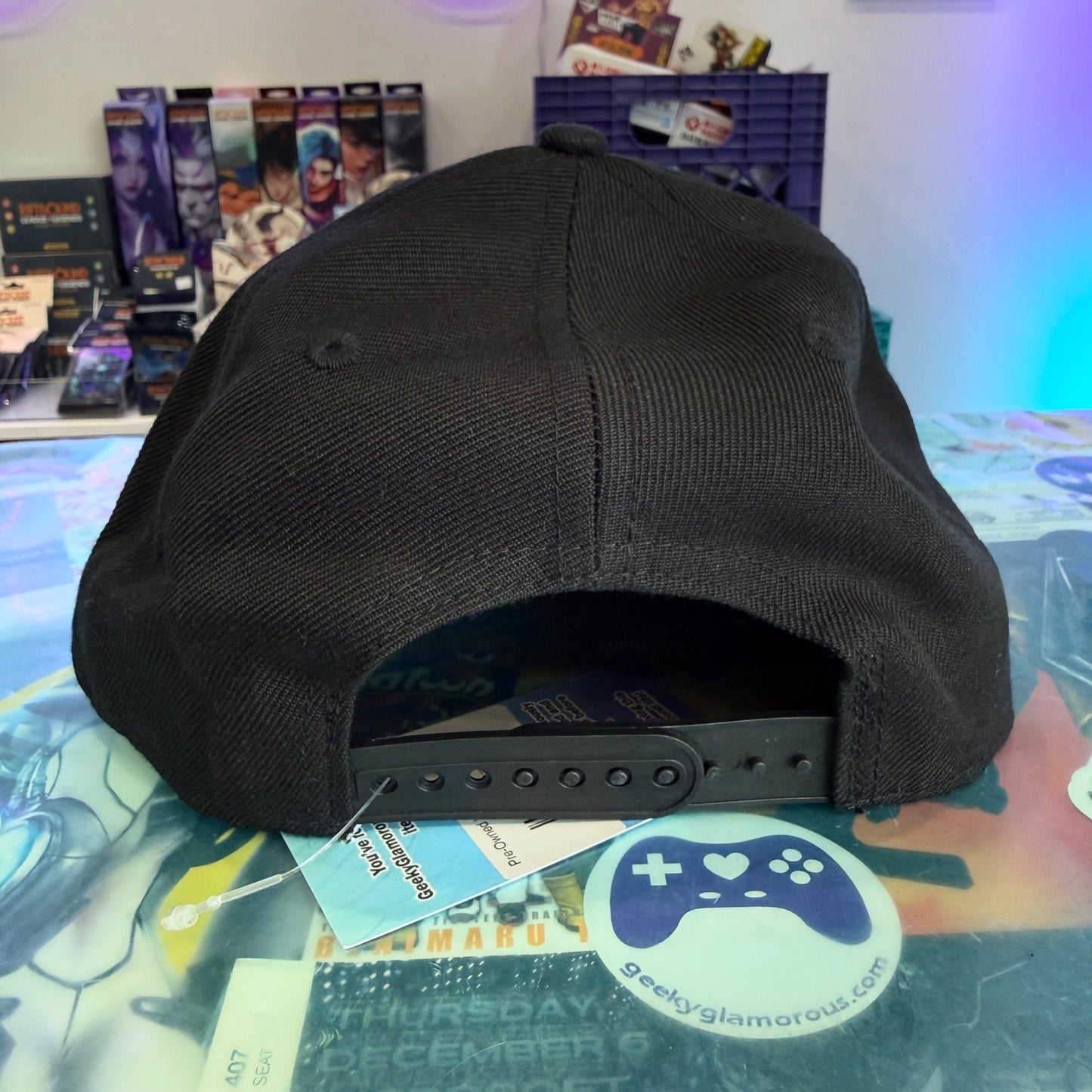 Back of black hat with snapback closure on a retail counter
