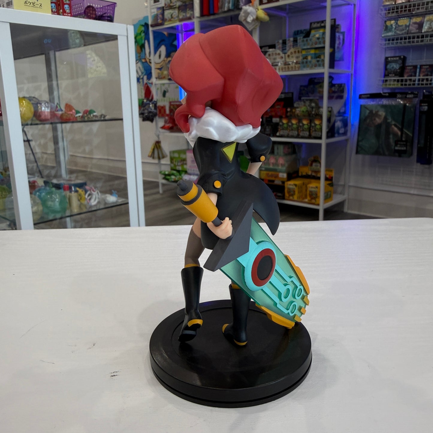 Red haired cartoon girl with futuristic sword on a black base with a shop in the background. 