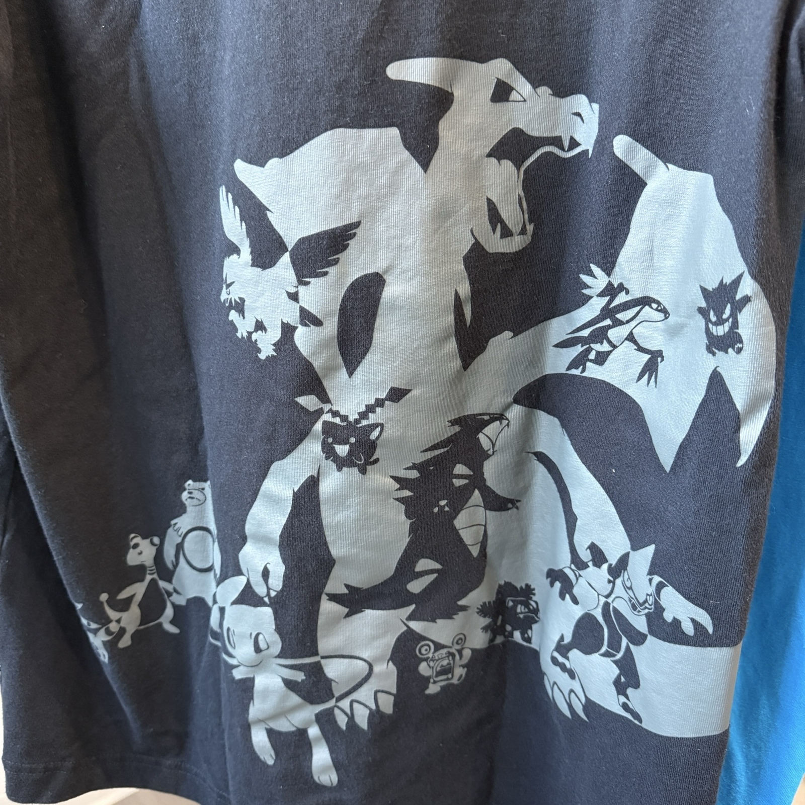 Upclose view of grey graphic of various Pokémon on black tshirt 