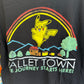 Close-up of a black graphic T-shirt featuring Pikachu flying over a rainbow and mountain scene with the text 'Pallet Town' and 'The Journey Starts Here!'.