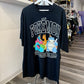 A black short-sleeve t-shirt with a colorful Pokémon graphic on the front, hanging on a white hanger in a retail store.