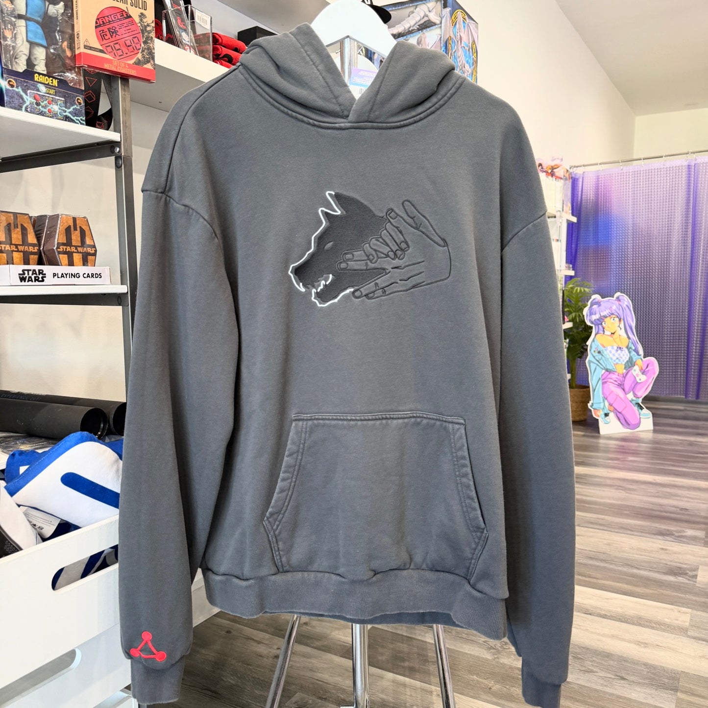 Grey hoodie with Jujutsu Kaisen wolf graphic on front in a store setting