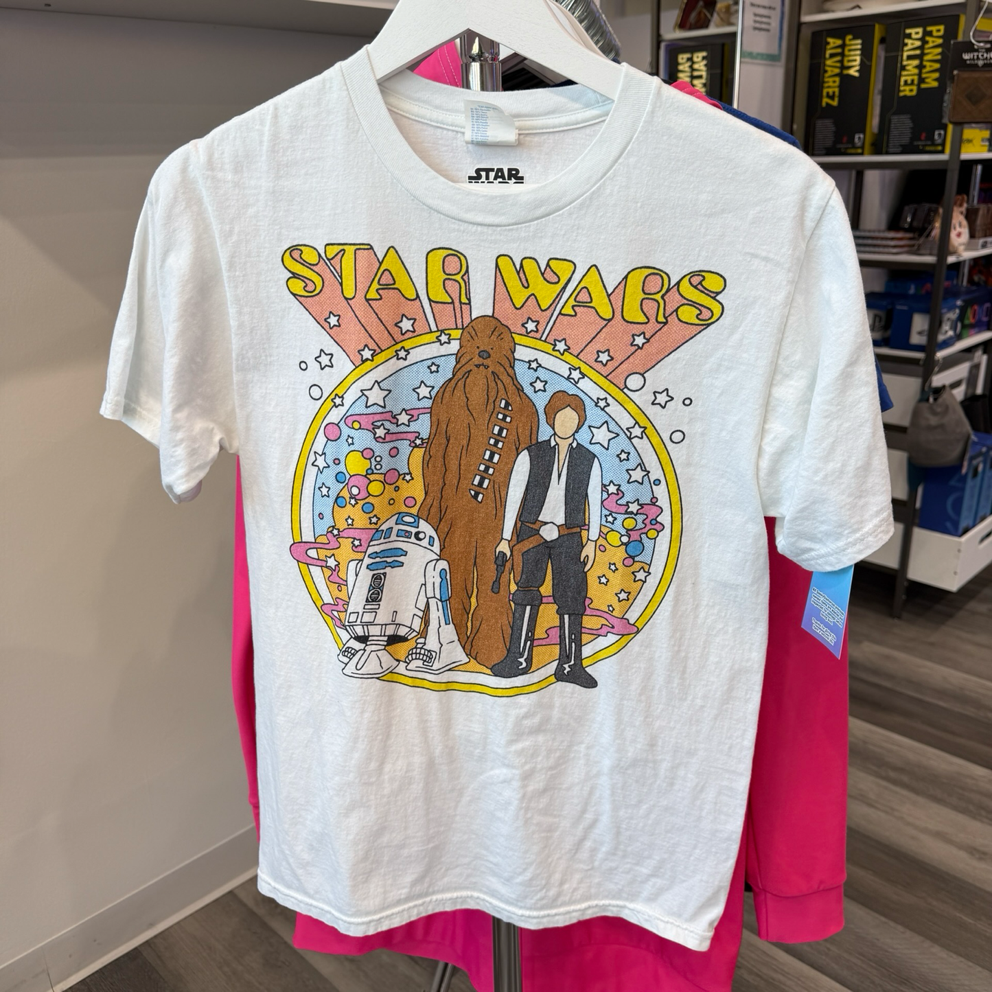 White tshirt with 1960s inspired graphic of R2D2, Chewbacca, and Han Solo from Star Wars. 