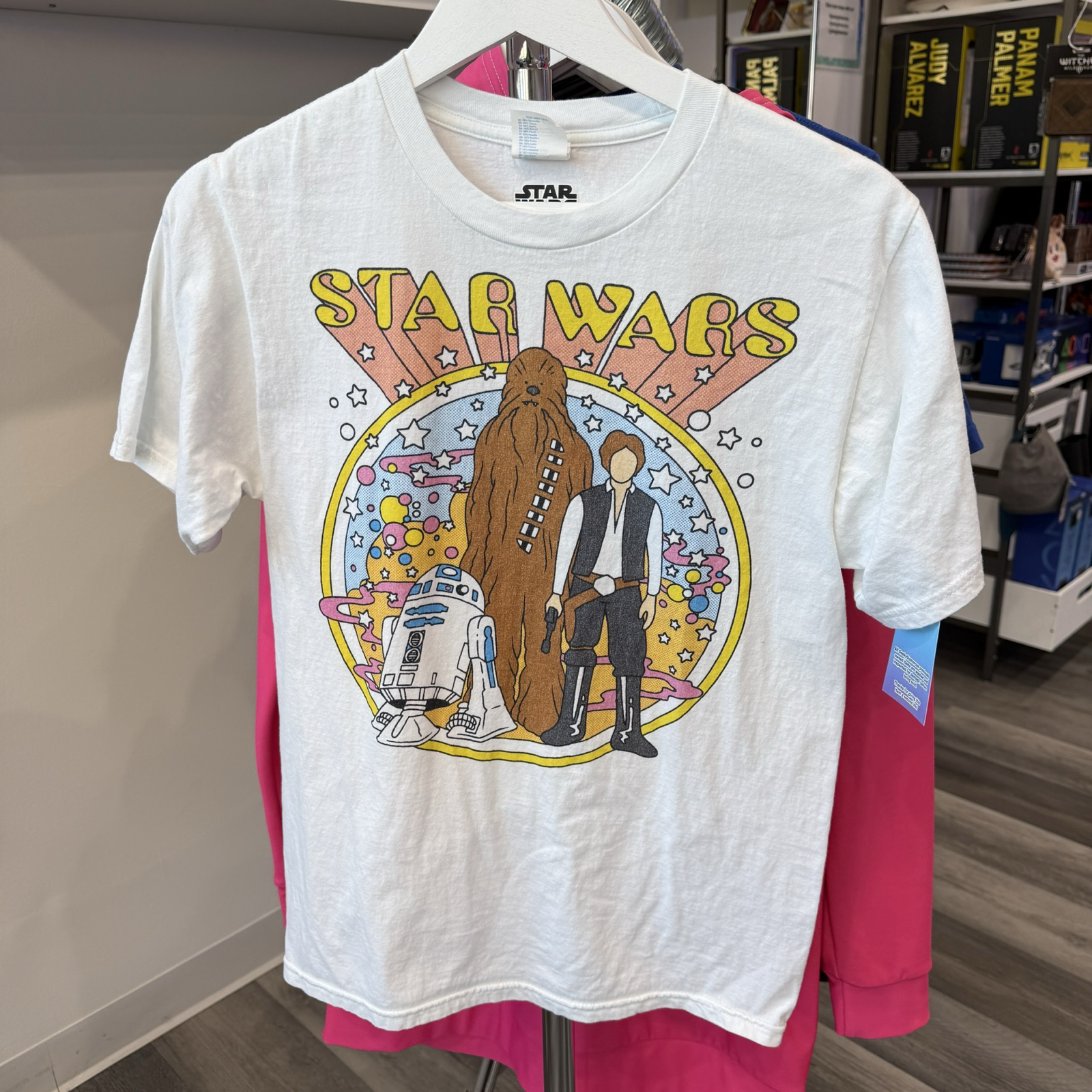 White tshirt with 1960s inspired graphic of R2D2, Chewbacca, and Han Solo from Star Wars. 