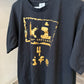 A dark charcoal gray t-shirt with a distressed gold graphic print on the front, featuring the text '4 life' and a stylized symbol. The shirt is shown hanging against a plain indoor wall.