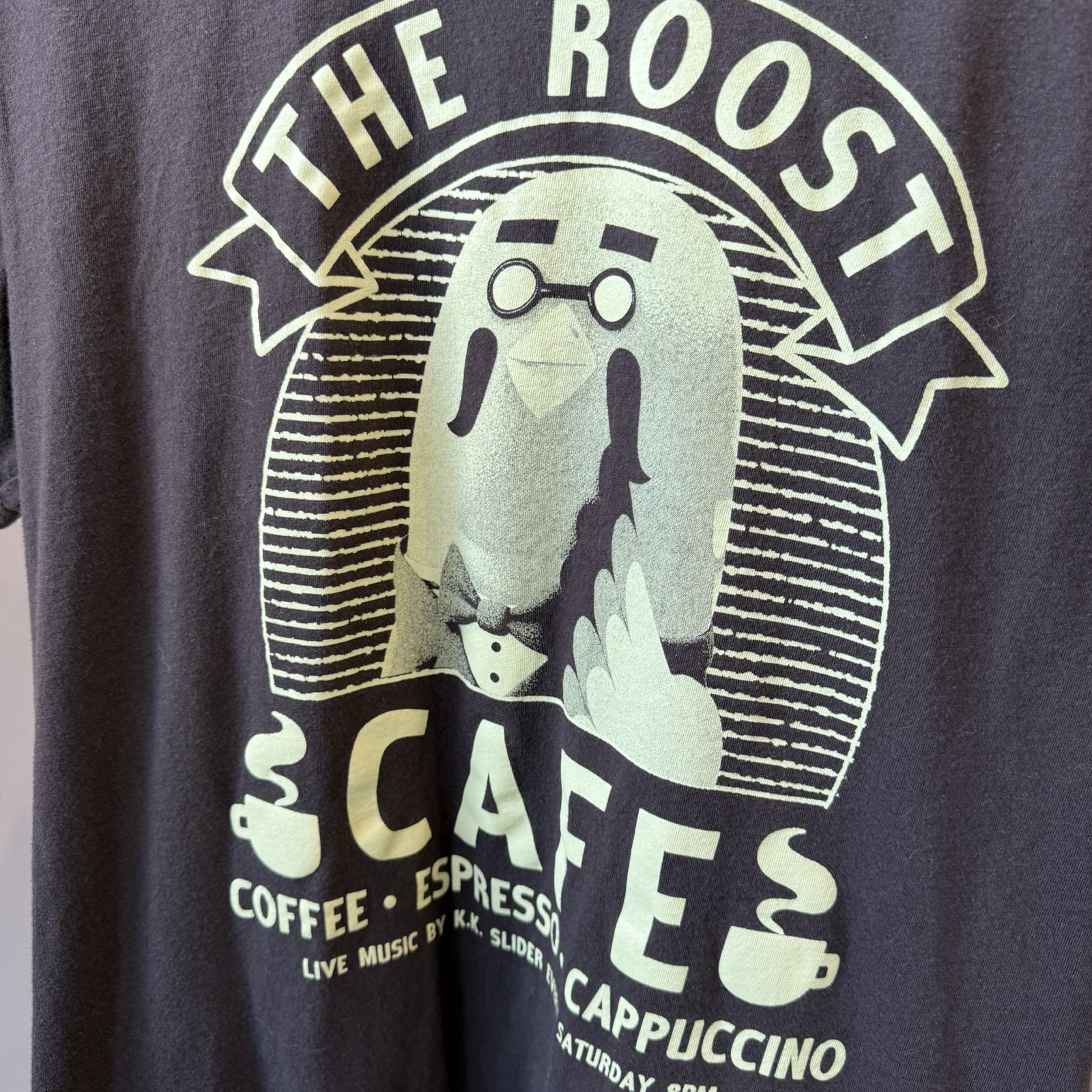 Close up shot of a dark brown tshirt with off-white color graphic of the pigeon character, Brewster from the video game series Animal Crossing