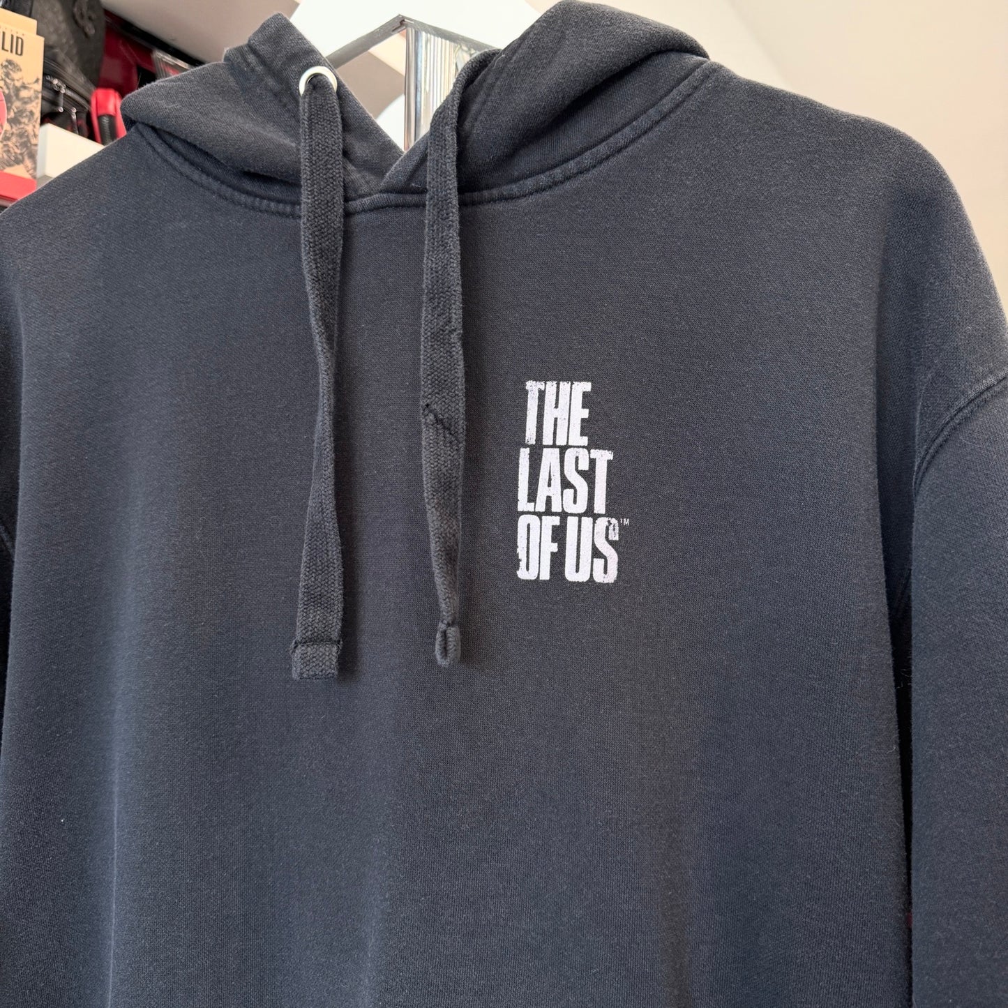 Gray hoodie with 'The Last of Us' logo on a hanger