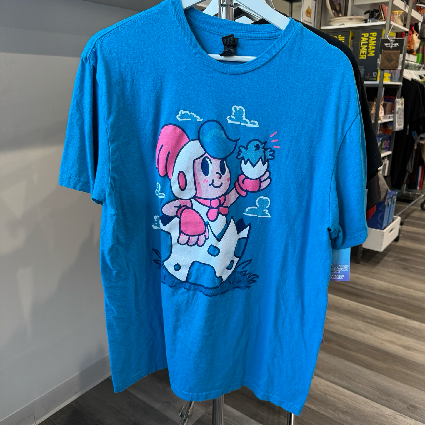 Teal blue color tshirt with white and red graphic of boy sitting in a egg from video game, Billy Hatcher and the Giant Egg. 