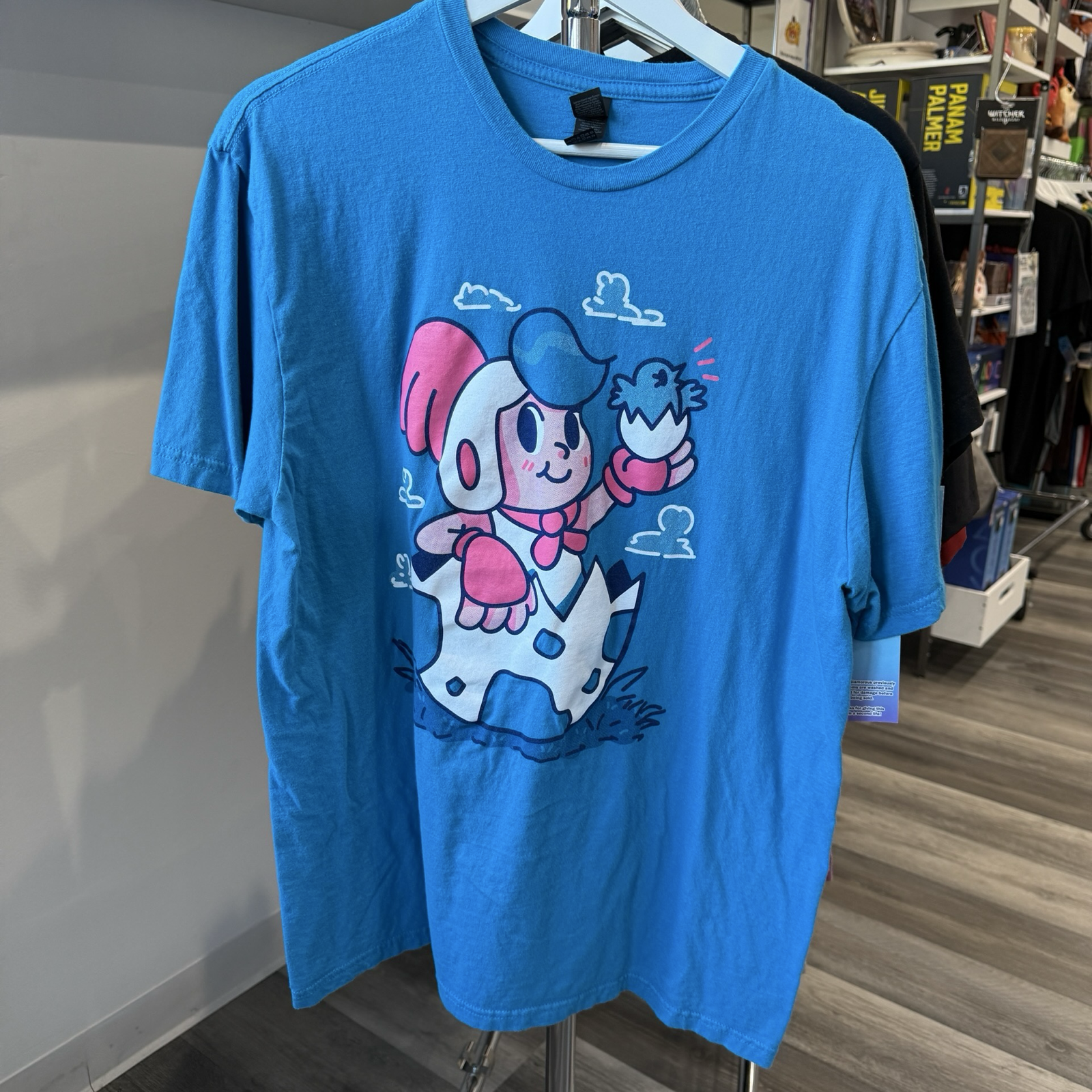 Teal blue color tshirt with white and red graphic of boy sitting in a egg from video game, Billy Hatcher and the Giant Egg. 