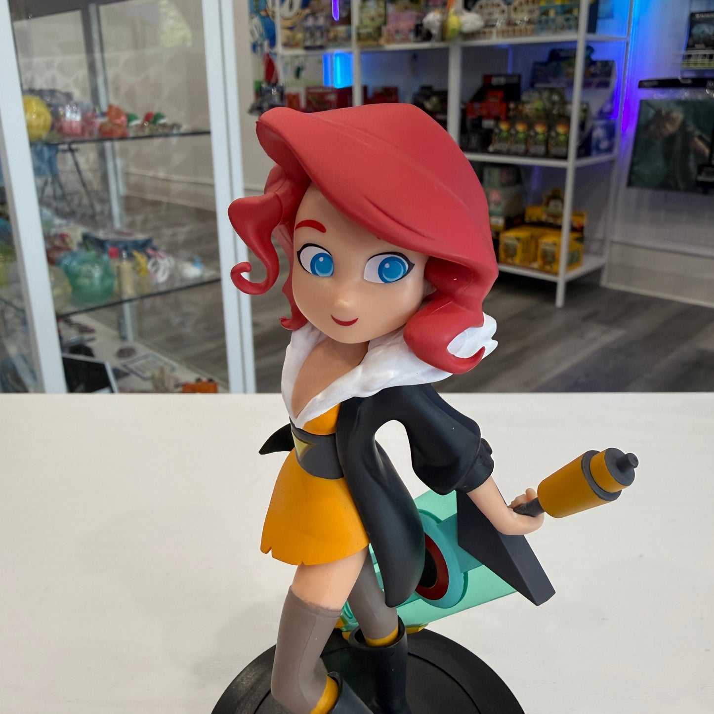 Animated character figurine with red hair and blue eyes, holding a weapon, in a store setting.