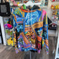 A colorful graphic hoodie featuring Yu-Gi-Oh! card art and character prints, hanging on a white hanger inside a retail store.