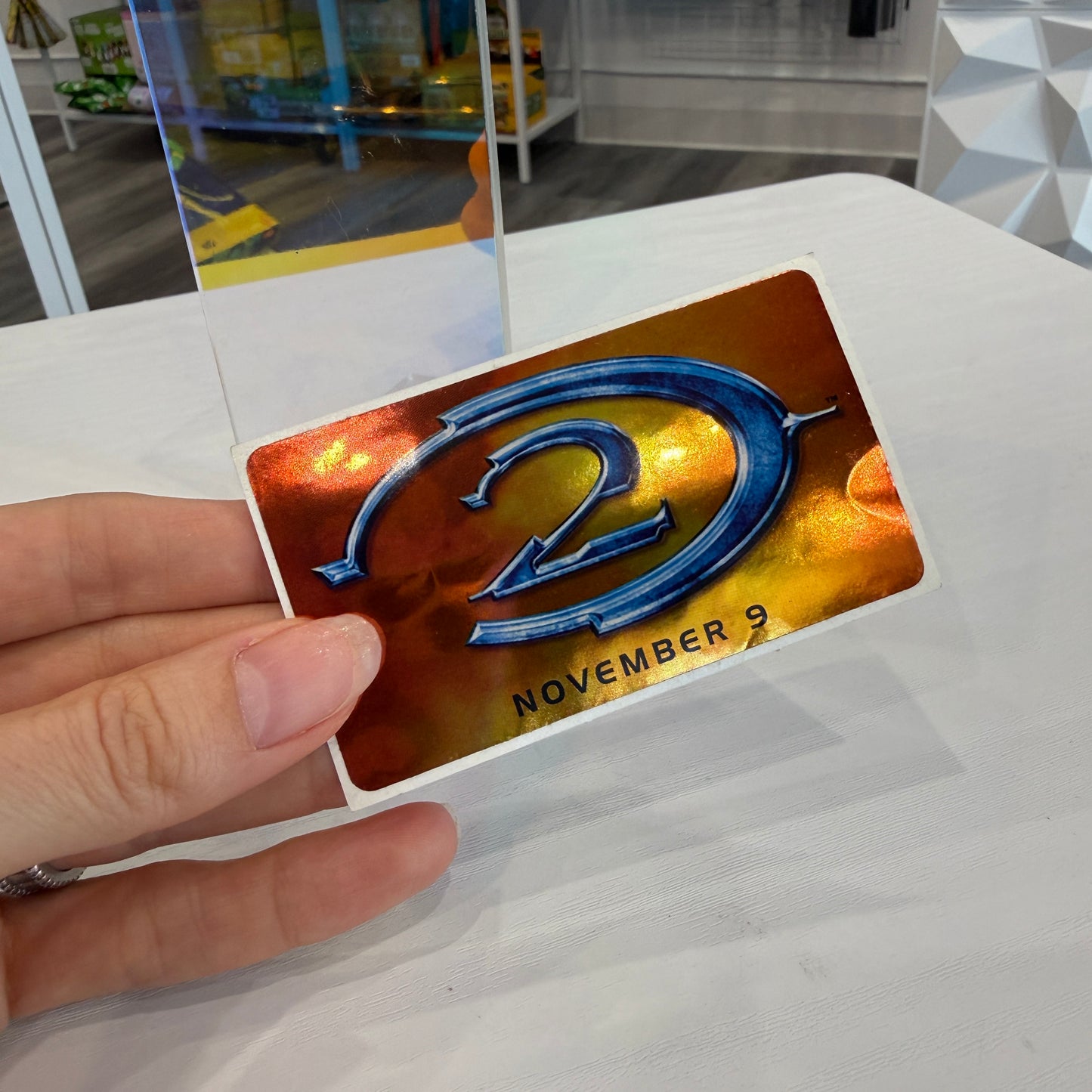 Hand holding metallic sticker of the Halo 2 logo 