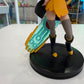 Red haired cartoon girl with futuristic sword on a black base with a shop in the background. 