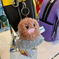 Fluffy, plush keychain of the Pokémon, Ditto hanging off a bag inside a store 