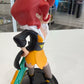 Red haired cartoon girl with futuristic sword on a black base with a shop in the background. 