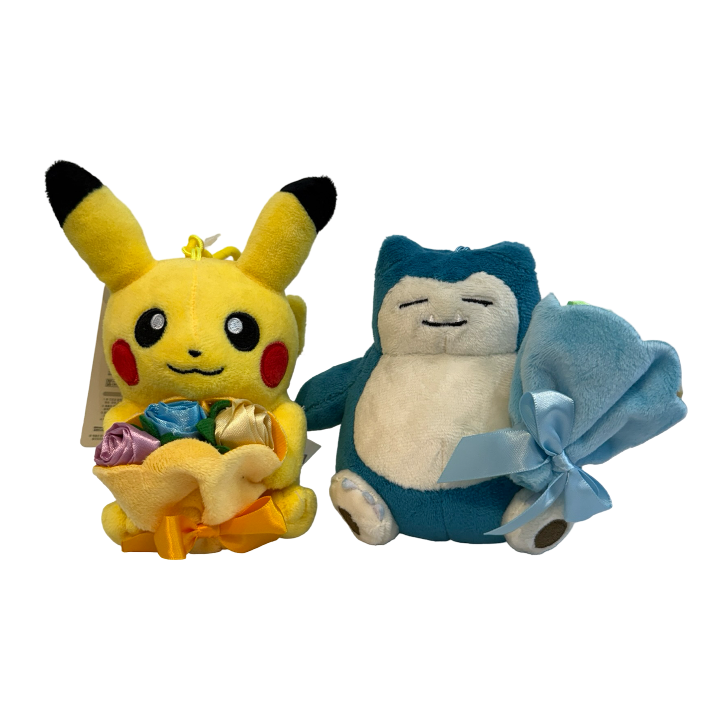 Plush keychains of Pokémon Pikachu and Snorlax holding bouquets of plush roses. 
