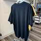 A large black oversized t-shirt hanging on a white hanger on a clothing rack inside a retail store.
