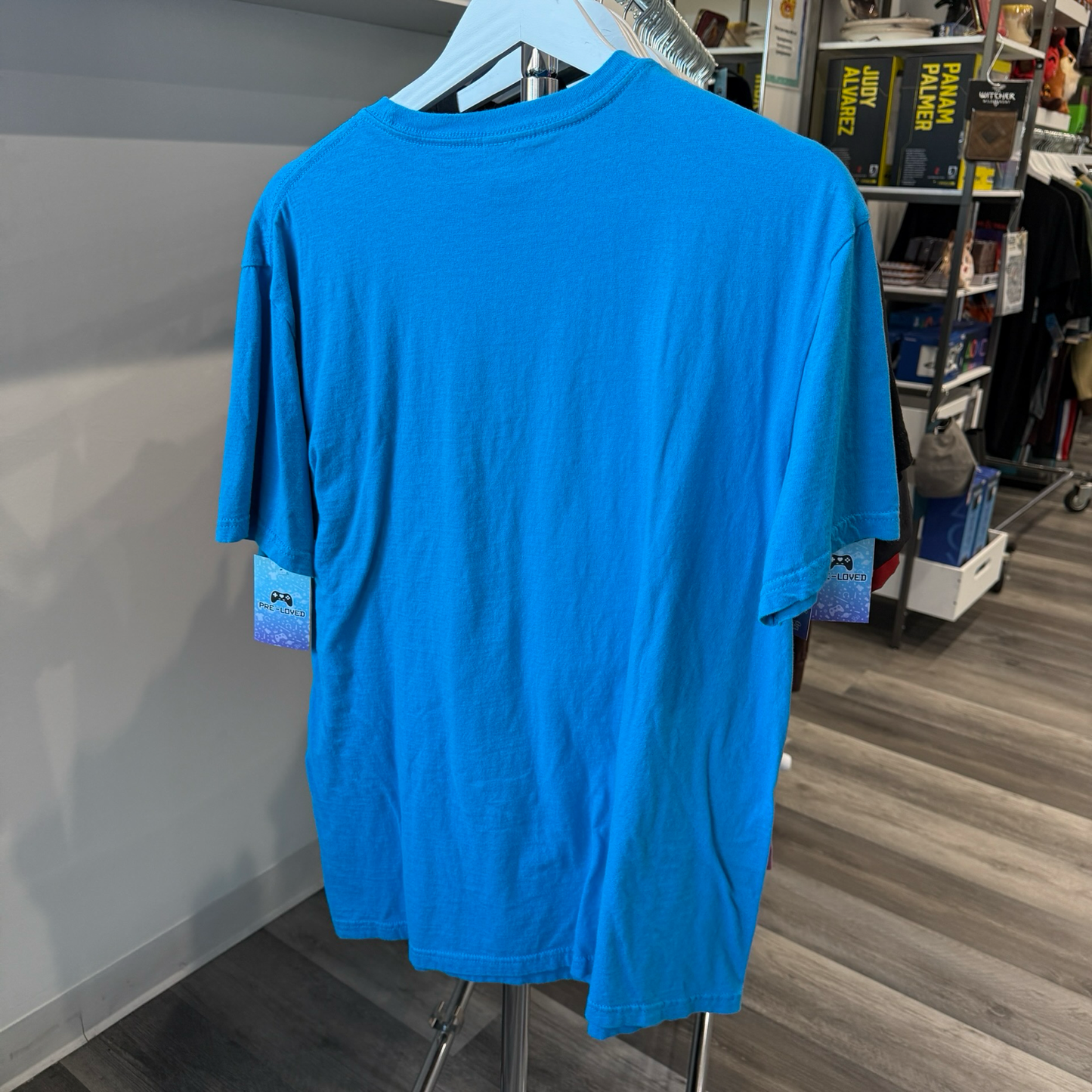 Back view of teal blue tshirt hanging in a store
