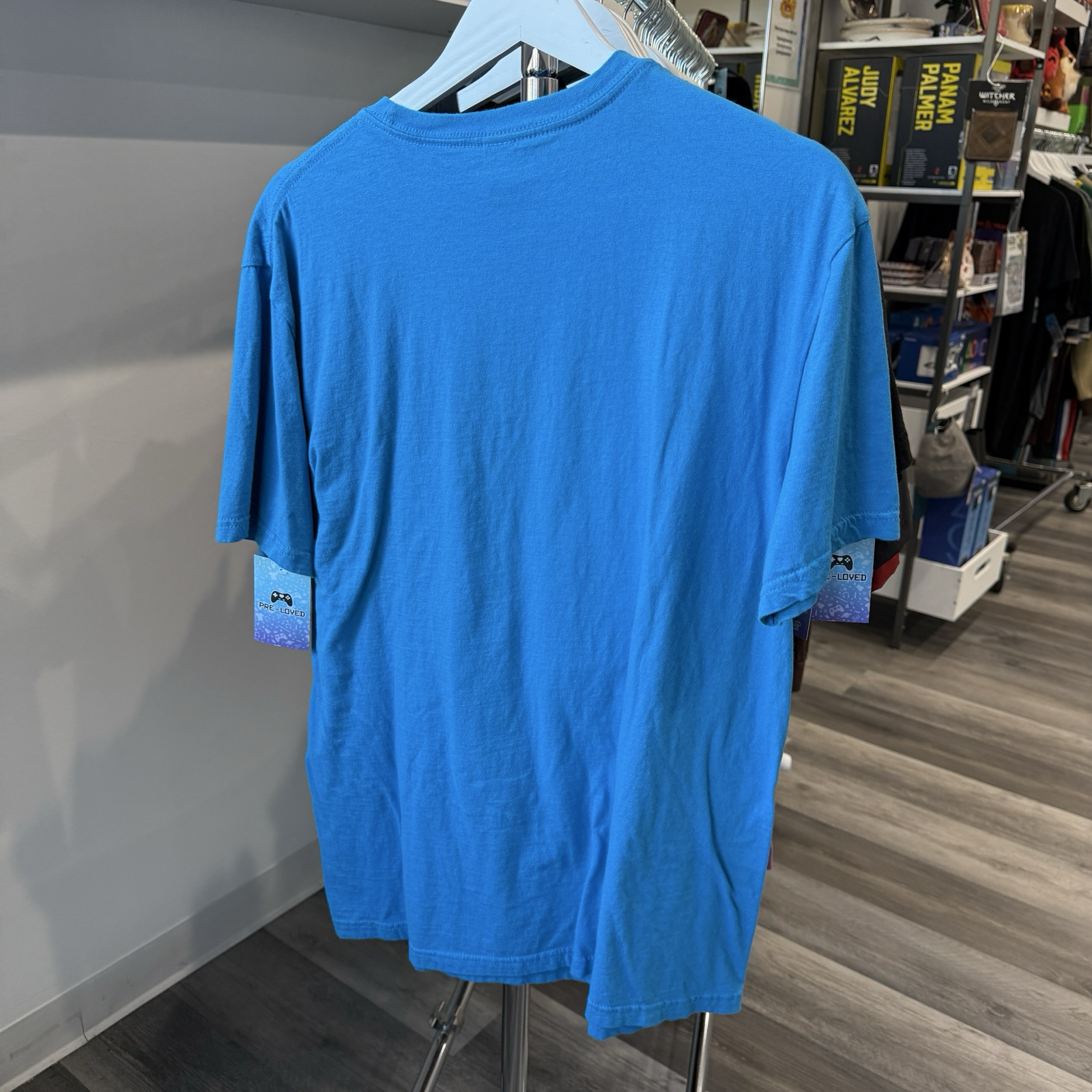 Back view of teal blue tshirt hanging in a store