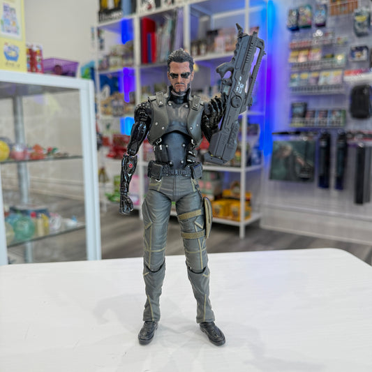 Action figure in a detailed costume holding a weapon on a white surface with shelves in the background.