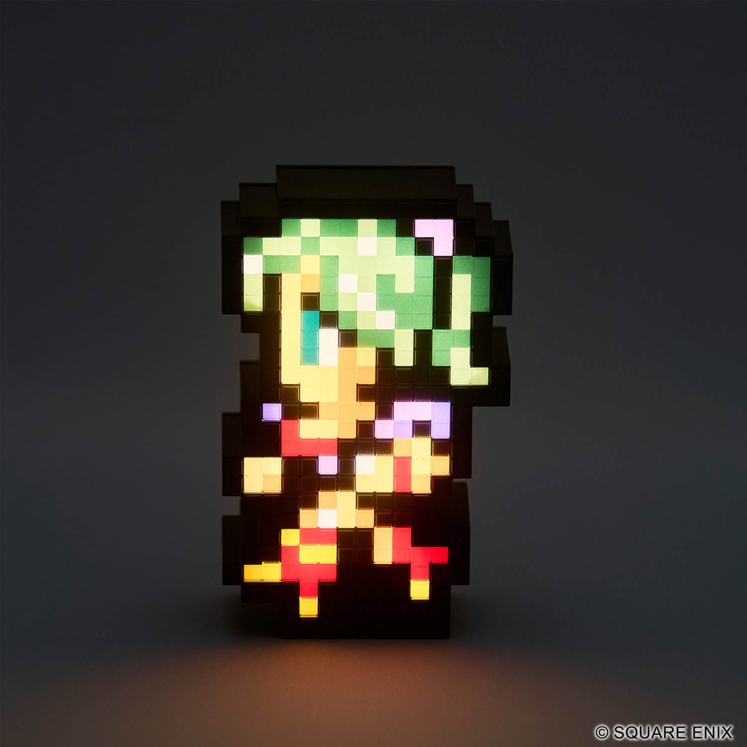 A pixel-art illuminated character figure stands against a dark gray background. The figure has green hair, a yellow face and torso, and red and purple accents, with a black blocky outline.