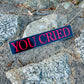 Sticker with 'YOU CRIED' text on a textured surface