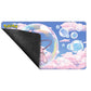 A rectangular Pokémon playmat with rounded corners, featuring a blue sky, pink clouds, and floating bubbles with a pink creature peeking from behind a large bubble. The left corner is folded over to show a dark gray textured backing.