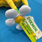 Close up of a white flower hat topper and hangtag featuring Pikmin branding and a yellow Pikmin character. 