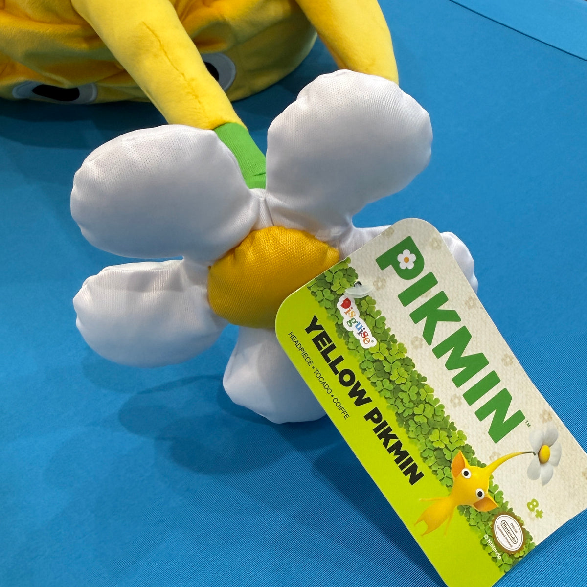 Close up of a white flower hat topper and hangtag featuring Pikmin branding and a yellow Pikmin character. 
