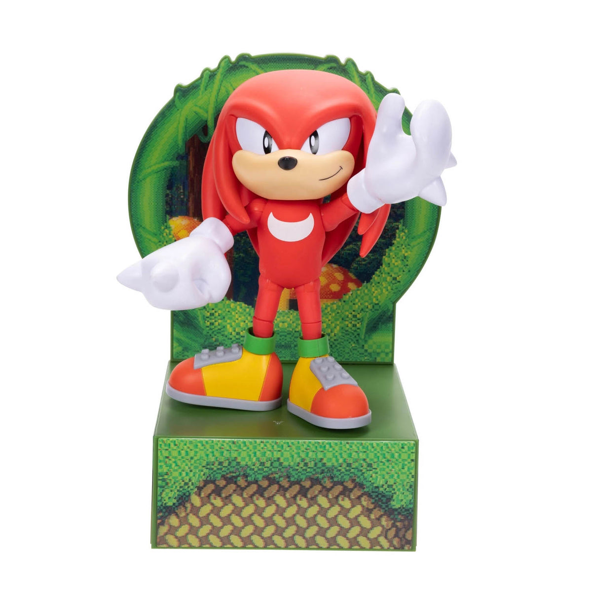 A Knuckles collectible figurine from Sonic the Hedgehog standing on a green textured base with a circular green backdrop. Knuckles is depicted with his signature red body, white gloves, yellow and orange sneakers, and green socks, set against a plain white background.