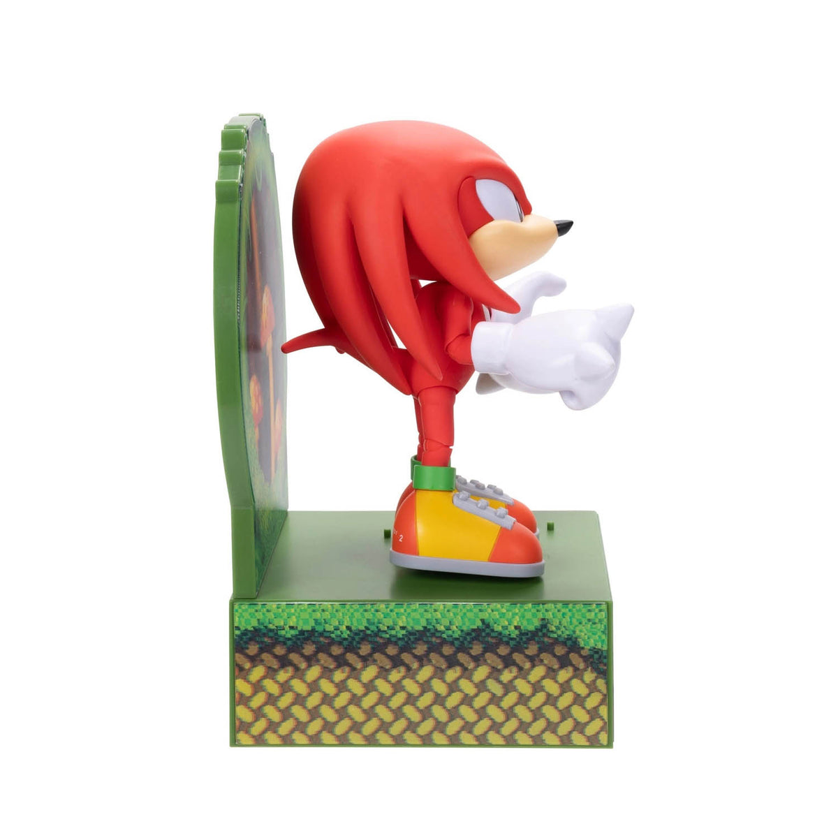 A Knuckles figurine standing on a green platform with a circular green backdrop, shown against a plain white background.