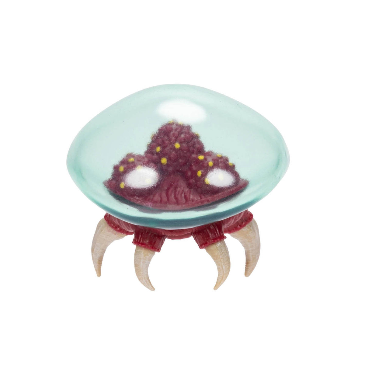 A small Metroid figure with a translucent aqua dome, a dark red textured body, and four curved cream-colored claws, shown on a plain white background.
