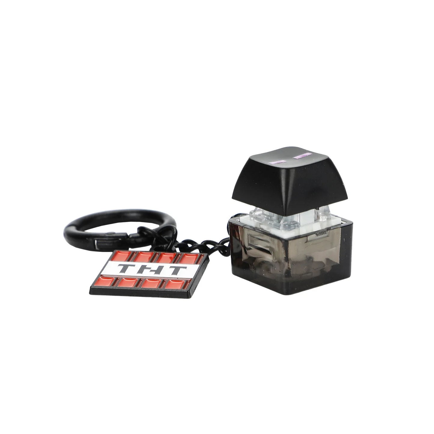 A miniature keychain shaped like a TNT explosive, featuring a black key ring, a small black and red TNT tile charm, and a small black keycap. 