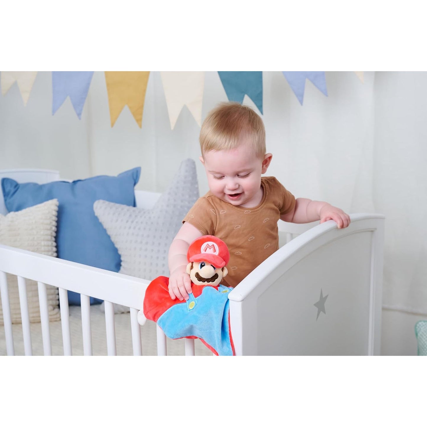 Infant child playing with Mario blanket toy in a white crib. 