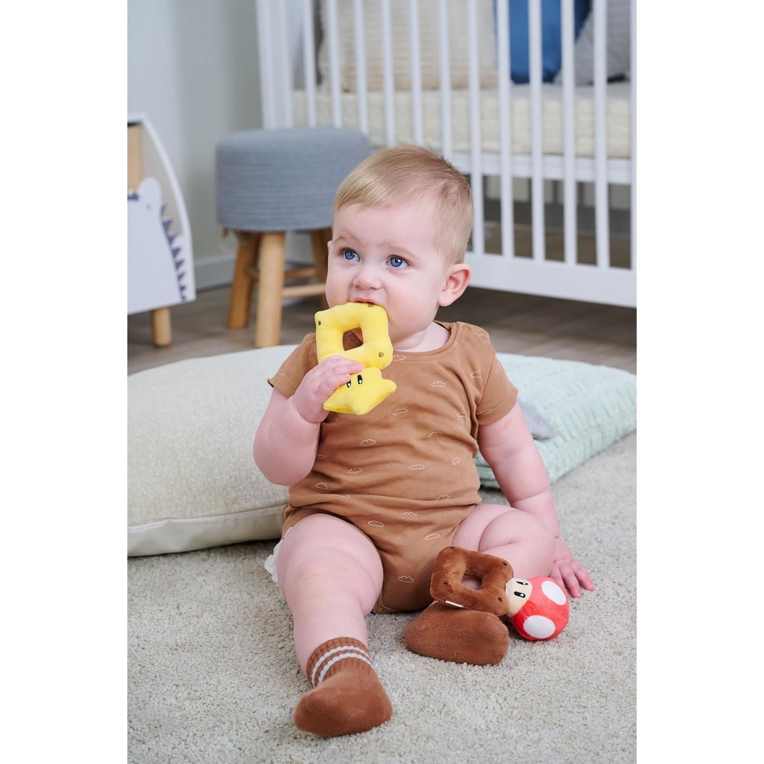 Infant baby chewing on a plush, yellow rattle of the Super Mario star