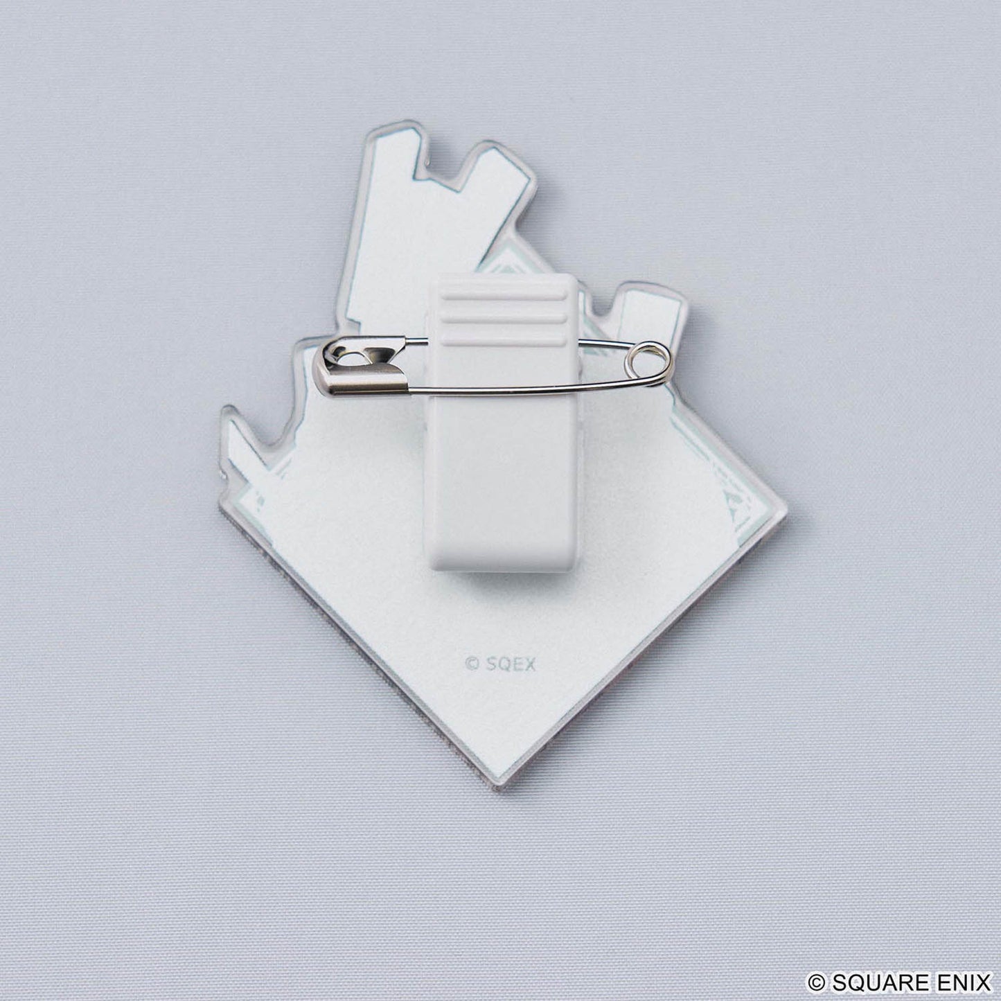 Backside of a acrylic pin with silver safety pin closure on a grey background