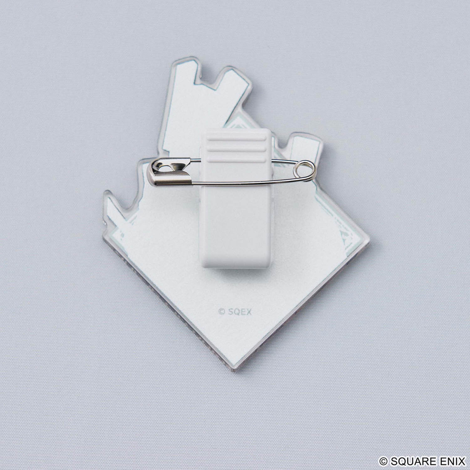 Backside of a acrylic pin with silver safety pin closure on a grey background