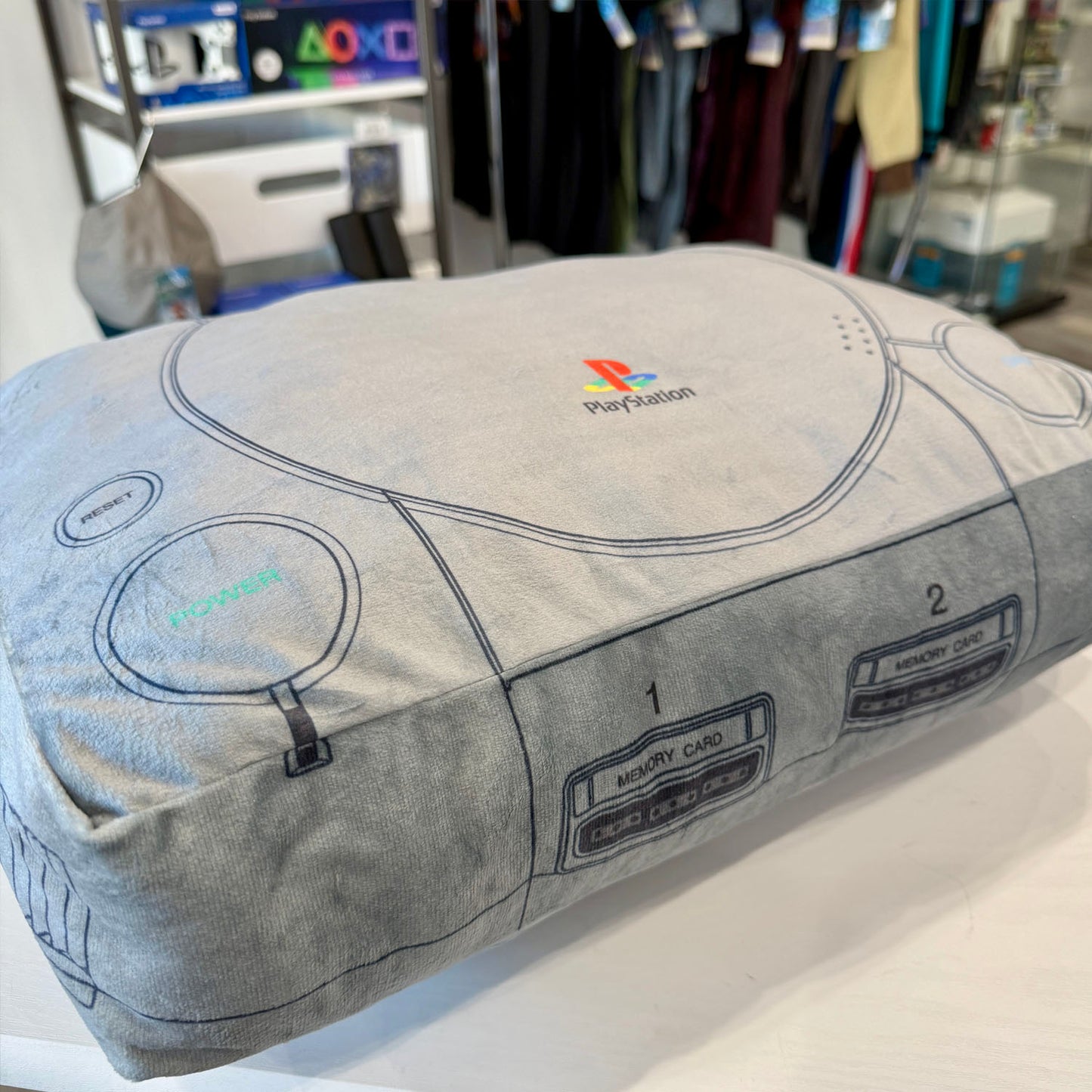PlayStation controller-shaped pillow with logo in a store setting
