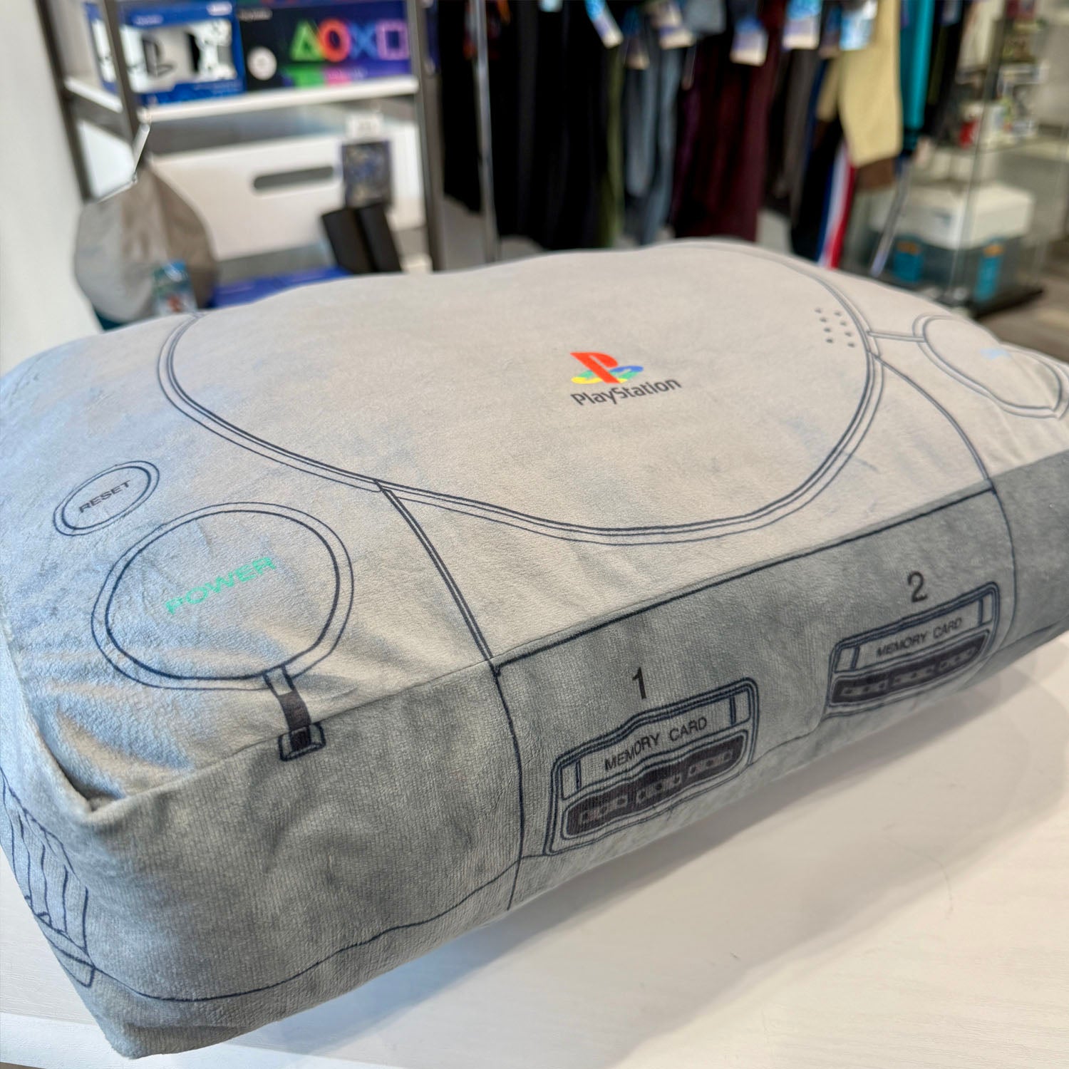 PlayStation controller-shaped pillow with logo in a store setting