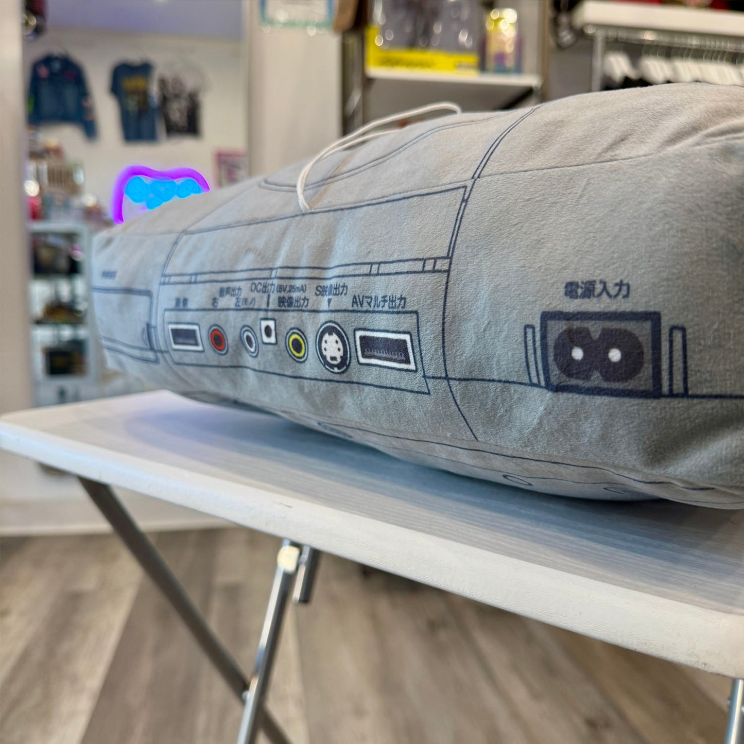 PlayStation controller-shaped pillow with logo in a store setting