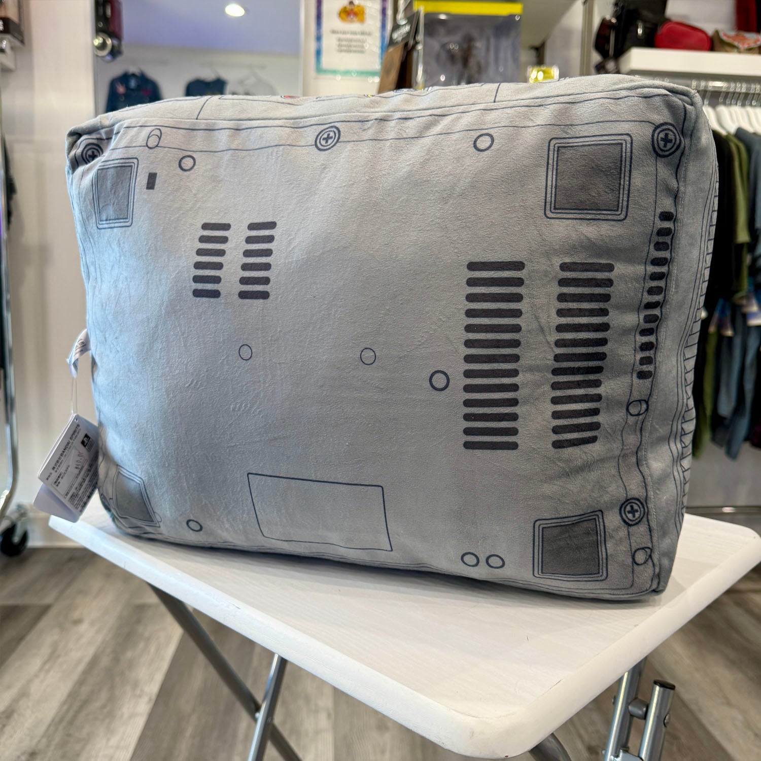 PlayStation controller-shaped pillow with logo in a store setting