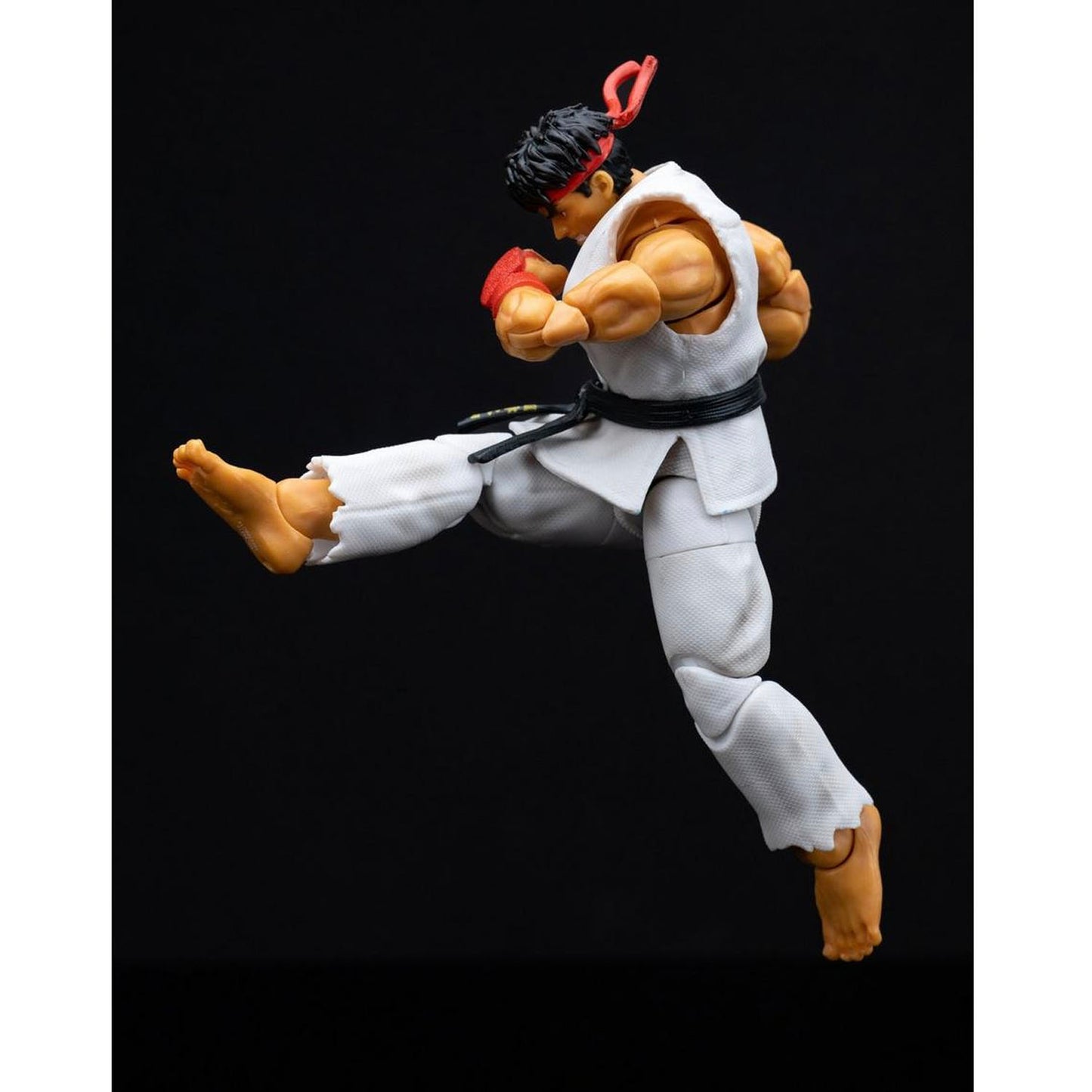 Action figure of Ryu from Street Fighter doing a dynamic pose on a black background