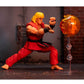 Street Fighter's Ken action figure posed in a fighting stance next to a translucent orange flame effect accessory on a clear stand, set against a dark, gritty urban backdrop.