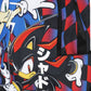 Close-up of a backpack featuring Sonic the Hedgehog and Shadow the Hedgehog artwork, with a black zipper pocket and bold red, blue, black, white, and yellow graphic print.