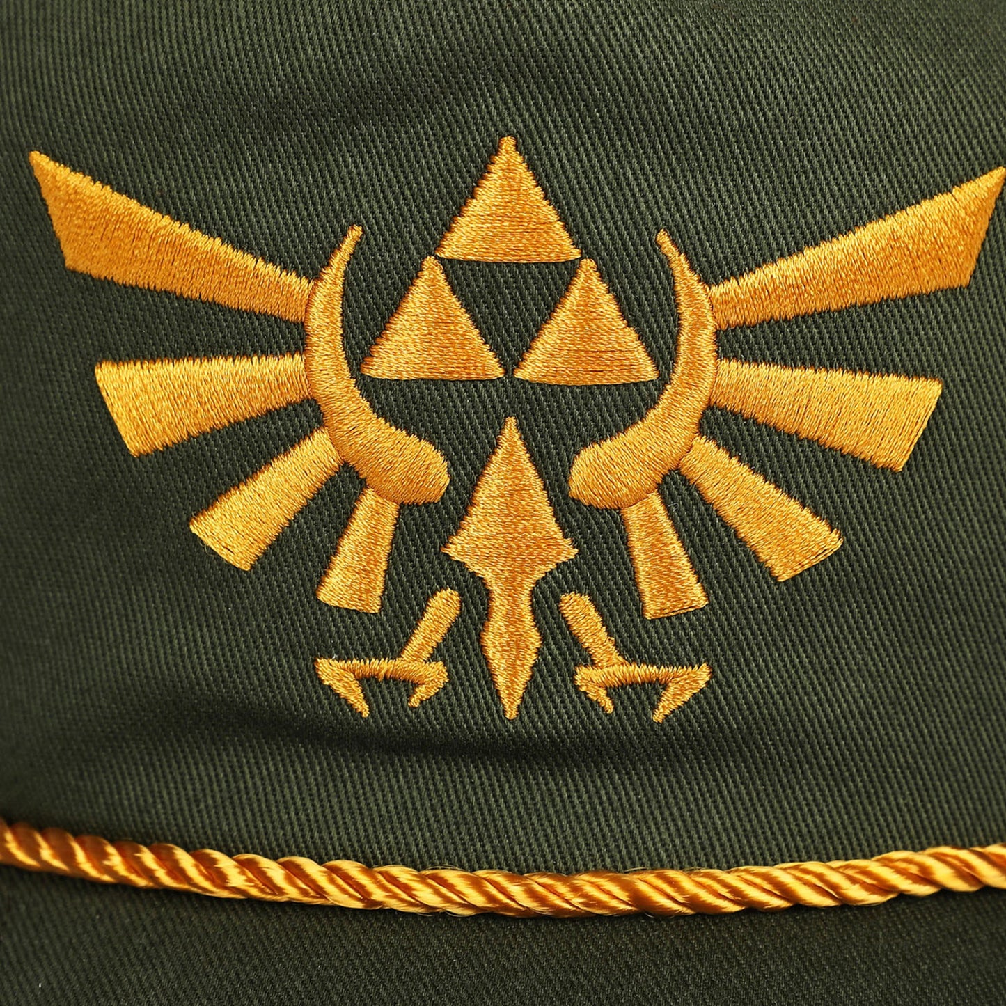 Close-up of a dark olive green fabric surface with a large embroidered gold emblem in the center and a matching gold braided trim along the bottom edge.